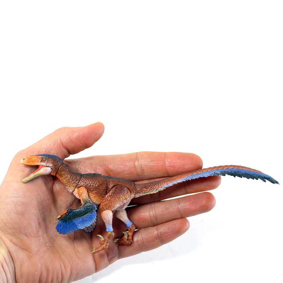 The dinosaur figure held in the hand.